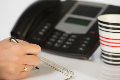 Cropped hands writing on book using pen in office