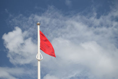 Low angle view of red flag against blue sky