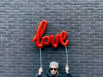 Portrait of person standing against brick wall