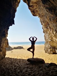 Full length of man on rock at beach against sky