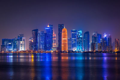 Coloful illuminated skyline of doha at night, qatar, middle east against dark sky