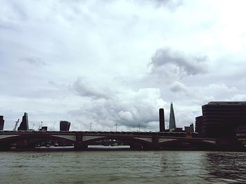 Bridge over river against cloudy sky