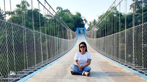 Full length of woman sitting on footbridge