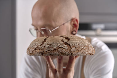 Man holding fresh sourdough bread in front of his face