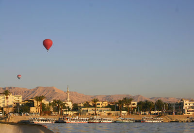 Hot air balloon flying over sea against sky in city