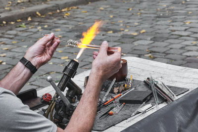 Process of artistic glass processing by burner flame. hands and workplace of mature glassblower