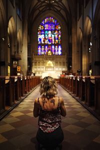 Rear view of woman praying in church