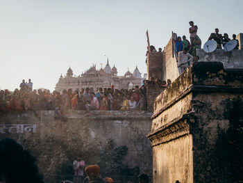 Group of people in front of historic building against clear sky