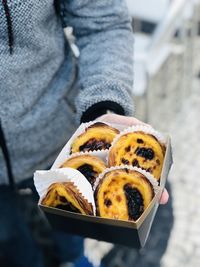 Midsection of person holding cakes pastel de nata