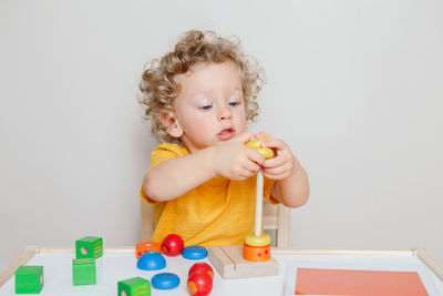  toddler playing with learning toy pyramid stacking blocks at home. early age education. 