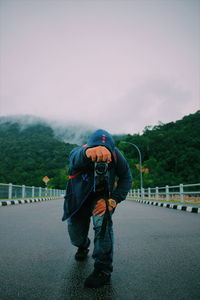 Man photographing on road against sky