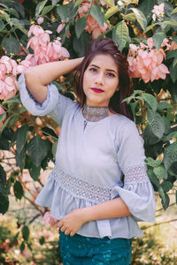 Portrait of a beautiful young woman standing by plants