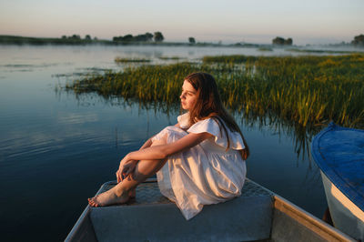 Portrait of young woman sitting by lake
