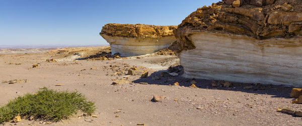 Rock formation at beach against clear sky during sunny day