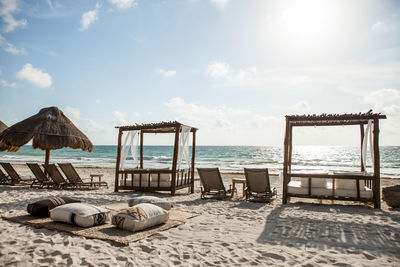 Deck chairs on beach against sky