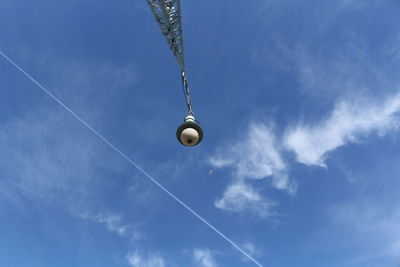 Low angle view of crane against vapor trail in sky