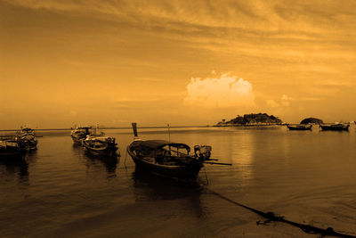 Boats moored in sea against sky during sunset