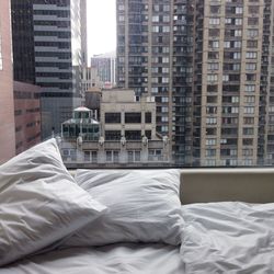 Bed and cushion by window with buildings in background