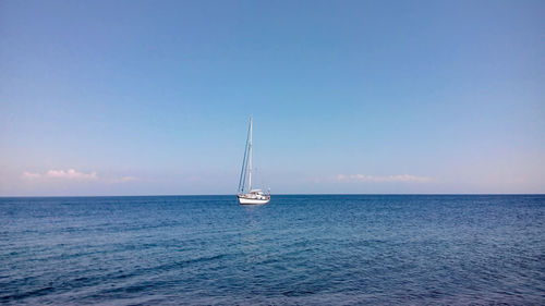 Sailboat sailing in sea against blue sky