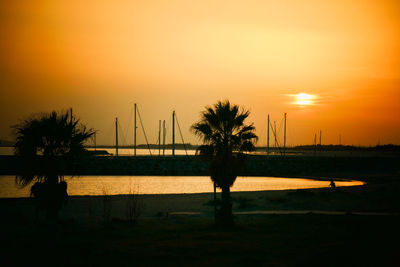 Silhouette palm trees by sea against sky during sunset