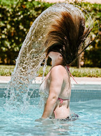 Full length of man splashing water in swimming pool