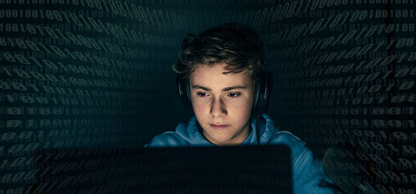 Teenager focused on computer display. green numbers on background. hacker attack,cyber crime concept