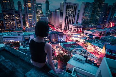 Rear view of woman looking at illuminated city buildings