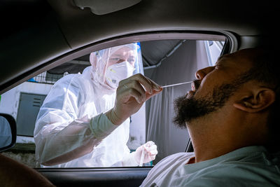 Midsection of doctor examining patient in car