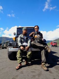 Young men on road against sky