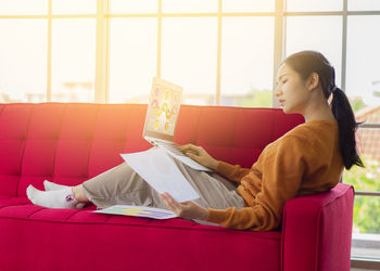 Side view of woman sitting on sofa