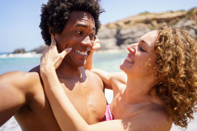 Side view of shirtless young woman sitting at beach