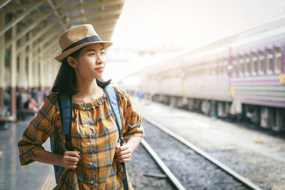 Young woman looking away while standing on railroad track