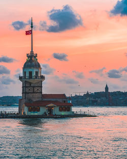 Building by sea against sky during sunset