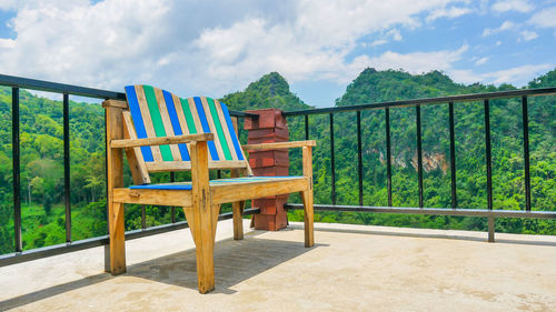 Empty chairs and table on beach against sky