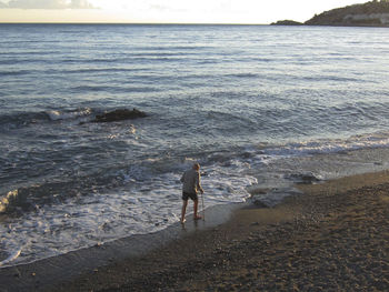 Rear view of man on beach against sky