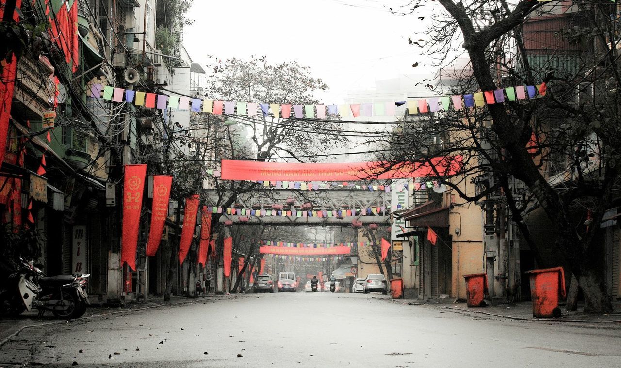 building exterior, architecture, built structure, street, city, tree, road, building, day, incidental people, flag, red, outdoors, residential building, residential structure, bare tree, city life, transportation, the way forward, car