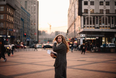 Woman standing on street with city in background