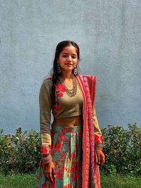 Portrait of smiling young woman standing against wall