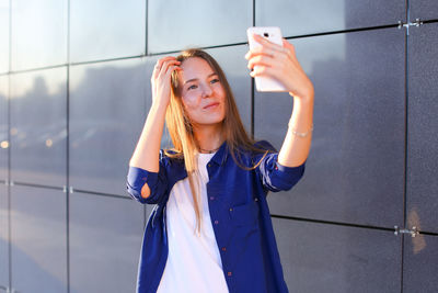 Portrait of young woman standing against wall