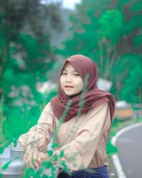 Portrait of beautiful young woman standing against plants