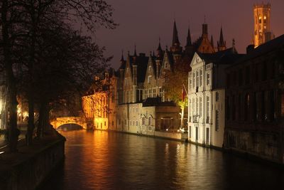 Bridge over river amidst buildings in city at night