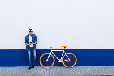 Full length portrait of young man standing against wall