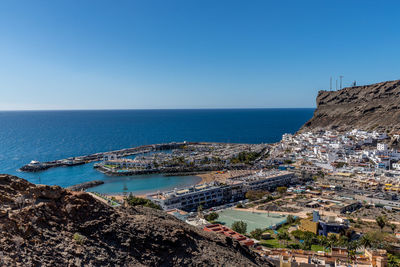 Aerial view of sea and buildings against clear blue sky