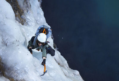 Young man climbing frozen waterfall in iceland