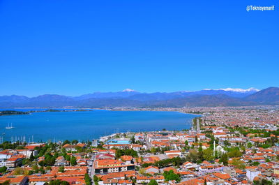 High angle view of townscape by sea against blue sky