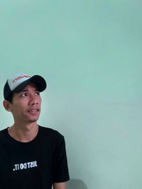 Portrait of young man standing against wall