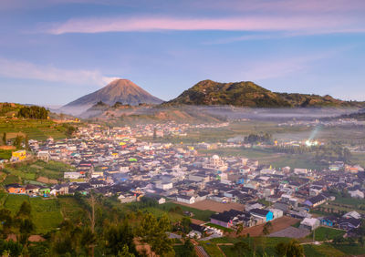 Aerial view of townscape and mountains against sky