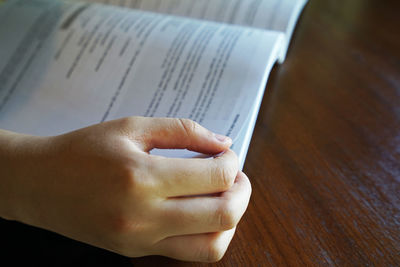 Close-up of hand holding book on table