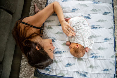 Loving mother gently touching newborn baby laying on stomach.