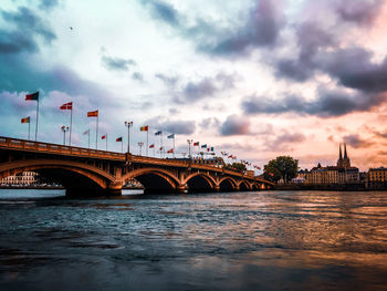 Arch bridge over river against cloudy sky